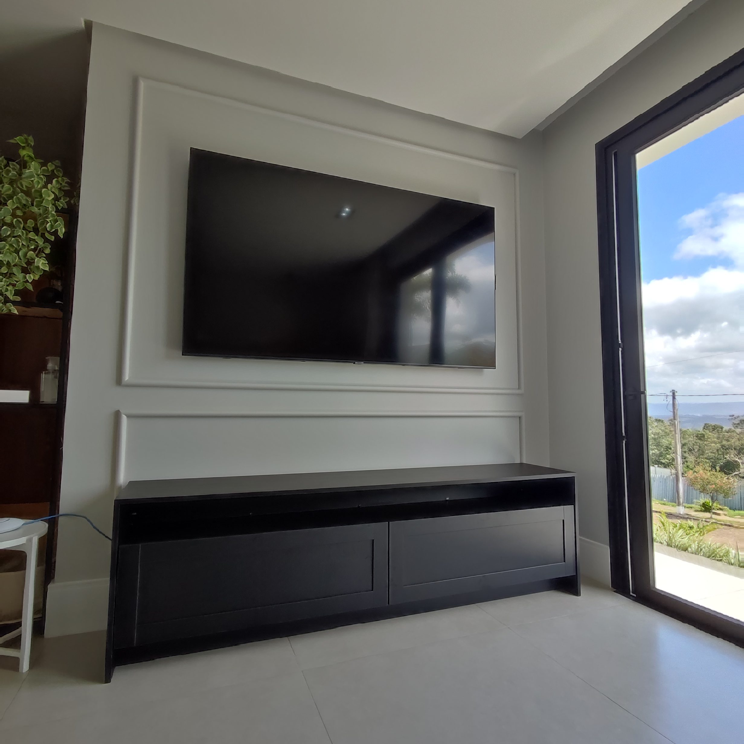 Painel de TV para Sala de Estar em São Leopoldo Painel de TV planejado com rack suspenso preto e detalhes em madeira, instalado profissionalmente.